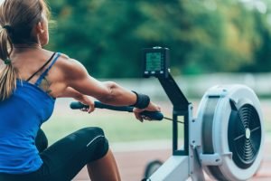 rowing machine workout in outdoors by mascular woman