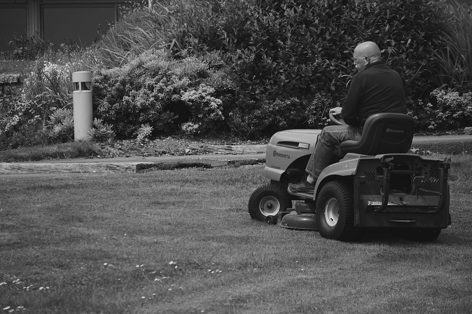 Old man using his ride-on mower to cut grass in his garden